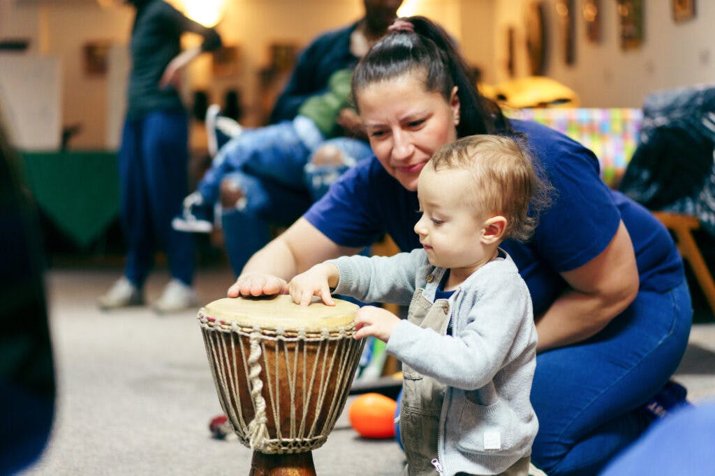 A mum and her infant child hitting an African drum at a Brixton Wings session